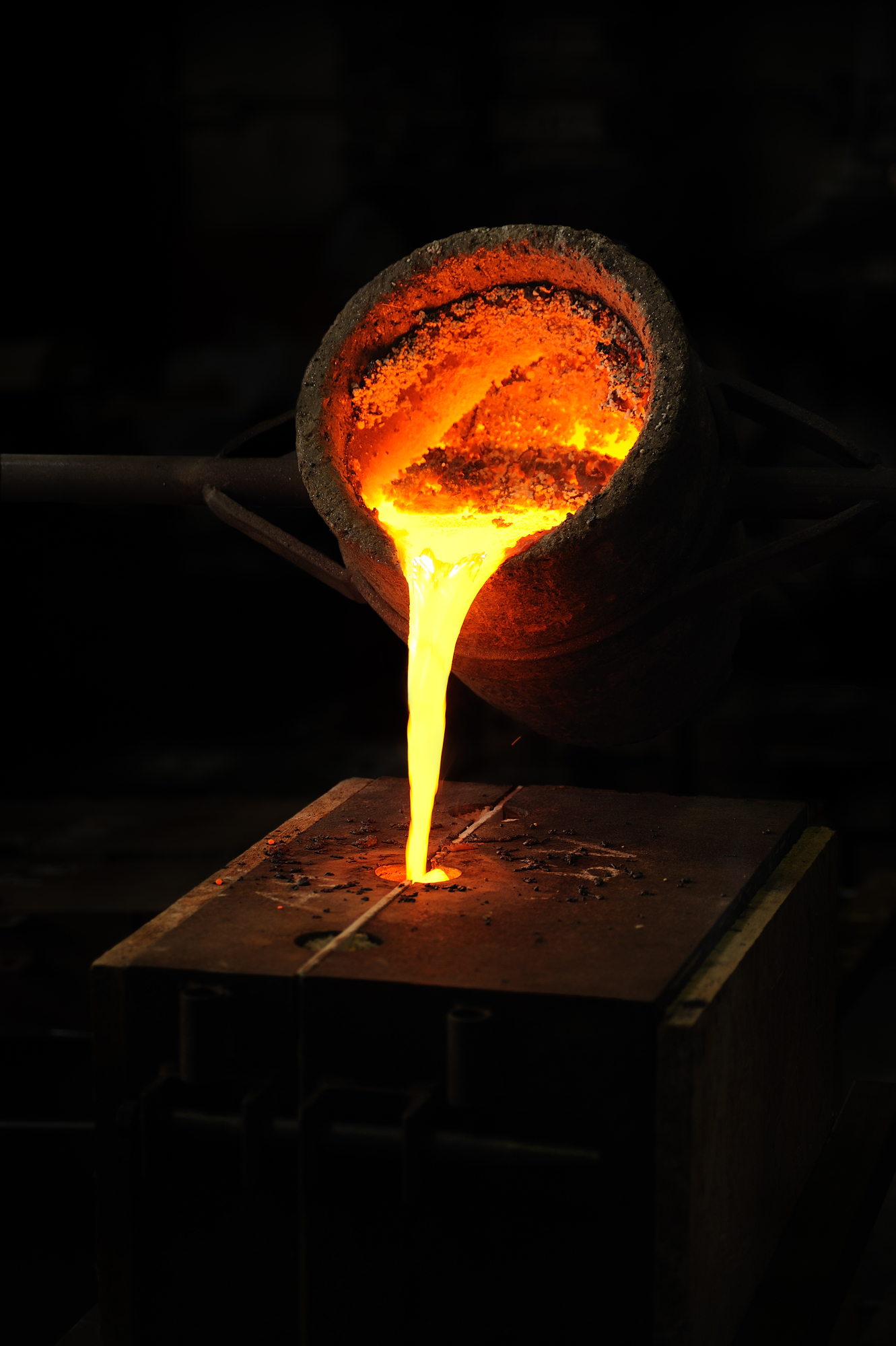 Foundry - molten metal poured from ladle into mould - lost wax casting Foundry - molten metal poured from ladle into mould - lost wax casting